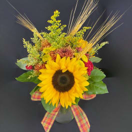 Sunflower arrangement in a glass vase with plaid ribbon