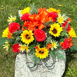 Bright sunflower and carnation arrangement with an orange bow in a patterned tote bag