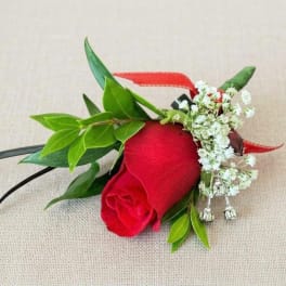 Red rose boutonniere with white baby's breath and green leaves