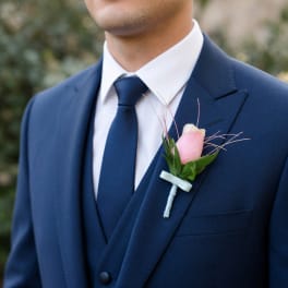 Man in a navy suit wearing a pink boutonniere