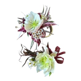 Two white floral wrist corsages with burgundy accents and ribbon on a white background