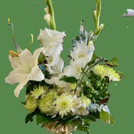 White floral arrangement in a glass vase with tall stems and green accents