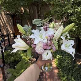 White lilies and pale pink flowers in a glass vase
