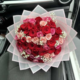 Bouquet of red and pink roses wrapped in translucent paper