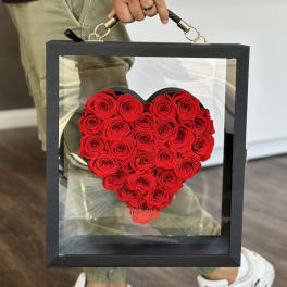 Heart-shaped arrangement of red roses in a black display box