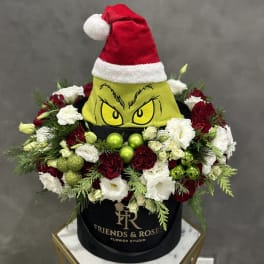 Holiday flower box with red and white roses and a Grinch hat topper
