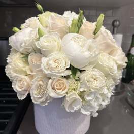 White and blush roses arranged in a white hatbox