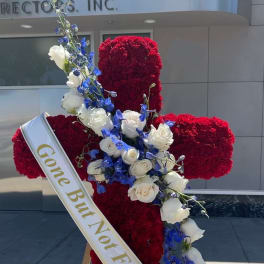 Red floral cross with white and blue flowers and a sash