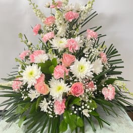 Pink and white floral spray with roses, carnations, and daisies