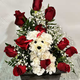 Red roses arranged around a white teddy bear in a wooden box