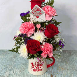 Bouquet of red roses, pink carnations, and white daisies in a mug