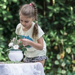 Girl arranging white flowers in a white vase outdoors