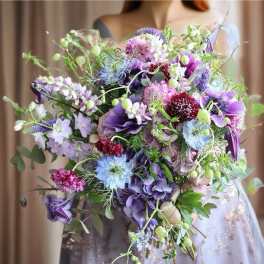 Large bouquet of purple, blue, and pink flowers held by a person