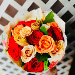 Bouquet of red, peach, and cream roses wrapped in white paper