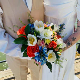 Bride and groom holding a colorful bouquet with roses and tulips