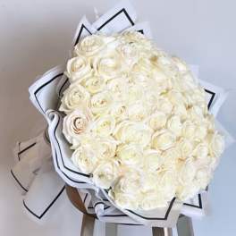 Large bouquet of white roses wrapped in white paper with black trim