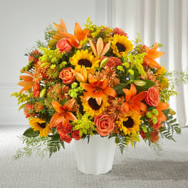 Orange and yellow mixed flower arrangement in a white vase