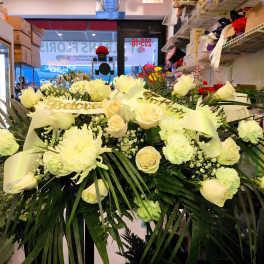 Large white floral spray with roses and ribbon in a shop