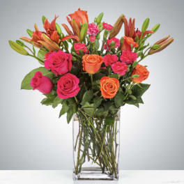 Bouquet of pink and orange roses with lilies in a clear glass vase