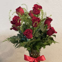 Red roses in a clear glass vase with a red ribbon