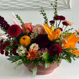 Mixed bouquet in a pink bowl vase with orange lilies and burgundy blooms