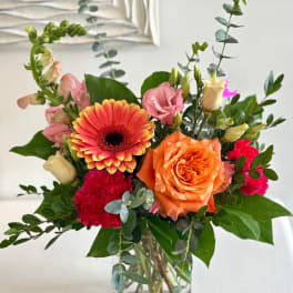 Mixed bouquet with orange gerbera, orange rose, pink lisianthus, and carnations in a vase