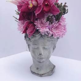 Pink orchid and chrysanthemum arrangement in a gray bust planter