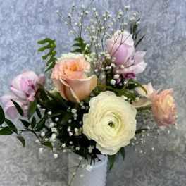 Pastel bouquet of roses and ranunculus in a white vase
