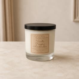 Vanilla pumpkin marshmallow candle in a clear glass jar with a black lid