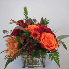 Orange and red mixed bouquet in a clear glass vase