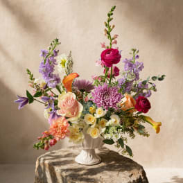 Colorful mixed flower arrangement in a white pedestal vase