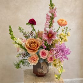 Mixed bouquet in a brown vase with pink, peach, and yellow flowers