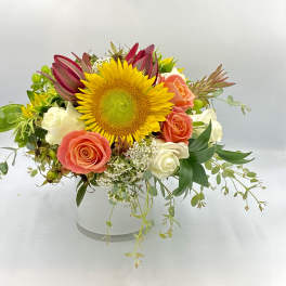 Mixed bouquet with a sunflower, roses, and white blooms in a white vase
