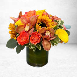 Bright mixed bouquet in a green glass vase with sunflowers and orange blooms