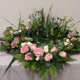 Large floral wreath with pink roses and greenery on a table