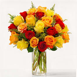 Bouquet of red, yellow, and orange roses in a clear glass vase
