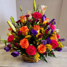 Basket arrangement of orange roses, purple lisianthus, and pink carnations