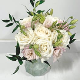 White and blush roses arranged in a glass vase