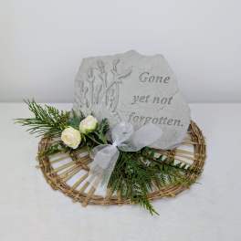Memorial stone with white roses and greenery on a wicker base