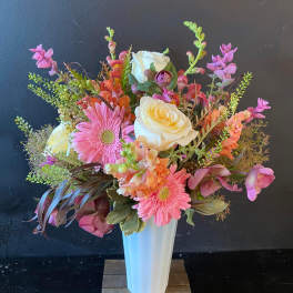 Pink and white mixed flower arrangement in a tall white vase