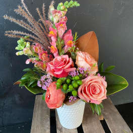 Pink roses and snapdragons arranged in a white vase