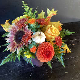 Autumn floral arrangement with a sunflower, yellow rose, and pumpkin accent in a vase