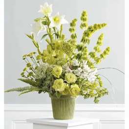 Green and white floral arrangement in a ribbed green vase