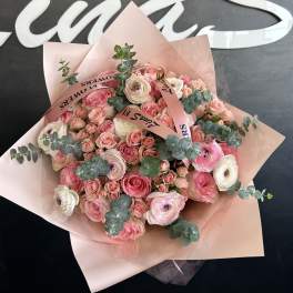 Pink and white bouquet of roses and ranunculus wrapped in blush paper