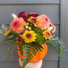 Fall bouquet in an orange pumpkin vase with pink and yellow flowers