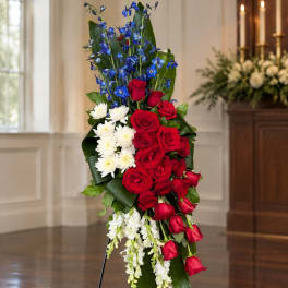 Tall standing floral spray with red roses, white flowers, and blue blooms