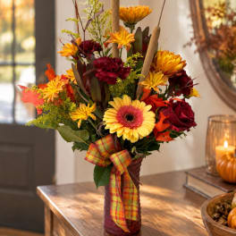 Autumn bouquet of yellow and burgundy flowers in a wrapped vase with plaid ribbon