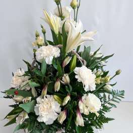 White lilies and carnations arranged in a basket with greenery