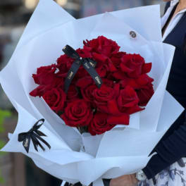 Bouquet of red roses wrapped in white paper with black ribbon
