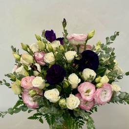 Bouquet of pink, white, and deep purple flowers in a glass vase